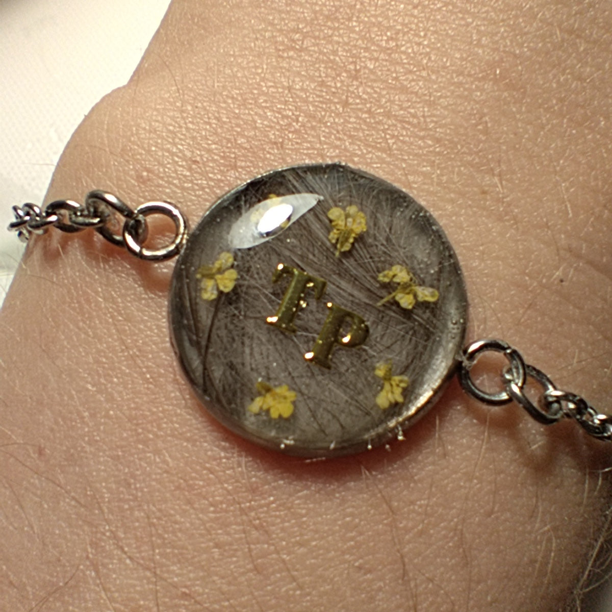 Bracelet en acier inoxydable, mèche de cheveux, lait maternel, poils et/ou cendres d'animaux en inclusion dans la résine.