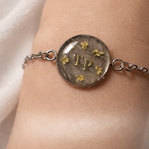 Bracelet en acier inoxydable, mèche de cheveux, lait maternel, poils et/ou cendres d'animaux en inclusion dans la résine.